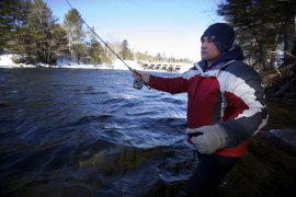 Scott Dionne of Mars Hill makes a cast at Grand Lake Stream on the frigid first day of traditional open water fishing in Maine in 2015. The Maine Department of Inland Fisheries and Wildlife has announced that this year's opening day has been moved up two weeks, from April 1 to tomorrow - March 17. BDN file photo.